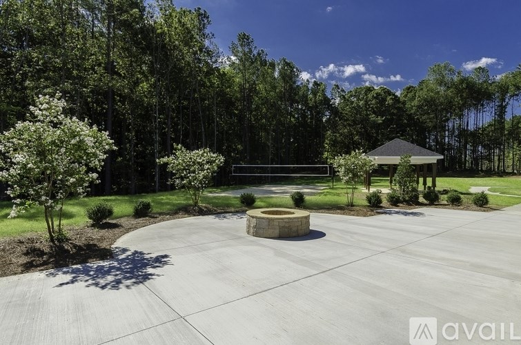 A gazebo is surrounded by a paved area and greenery.