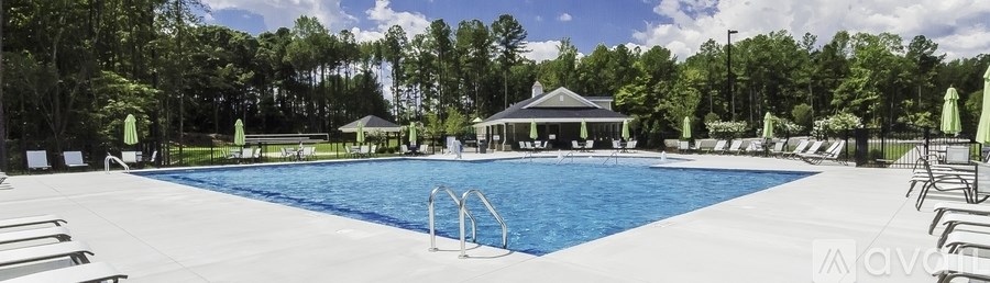 A large swimming pool surrounded by trees and lounge chairs.