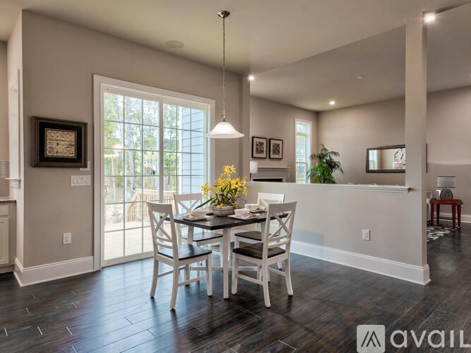 A dining room with a table set for two and a view of the backyard through the sliding glass doors.