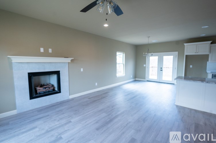 A spacious living room with a fireplace and a ceiling fan.