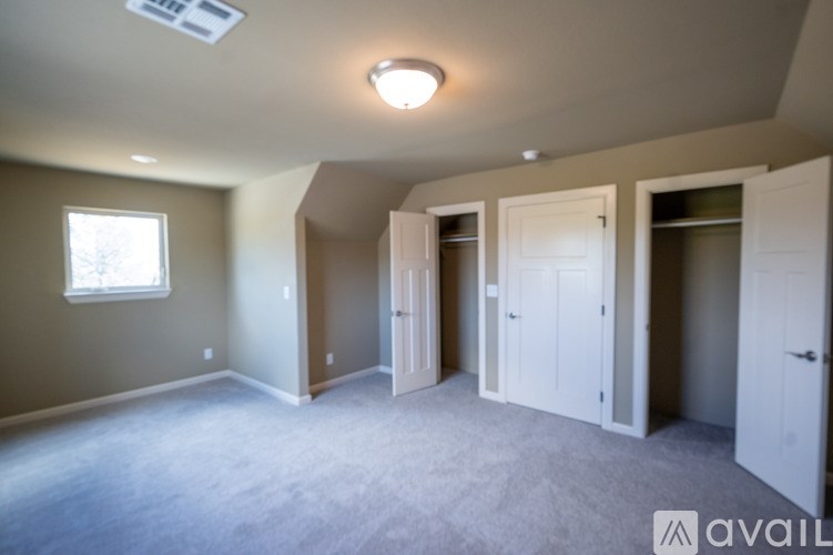 A spacious room with a window, carpeted floor, and a skylight.