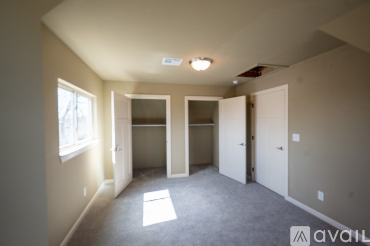 A room with a carpeted floor and a window on the left side.