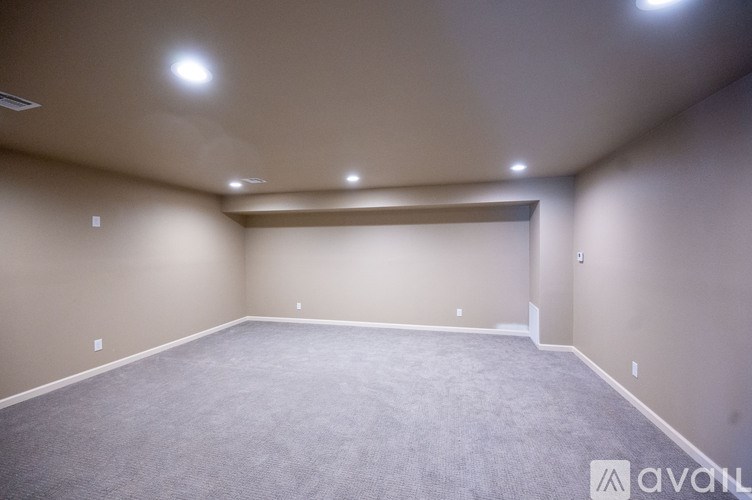 A spacious room with carpeted floor and recessed ceiling lights.