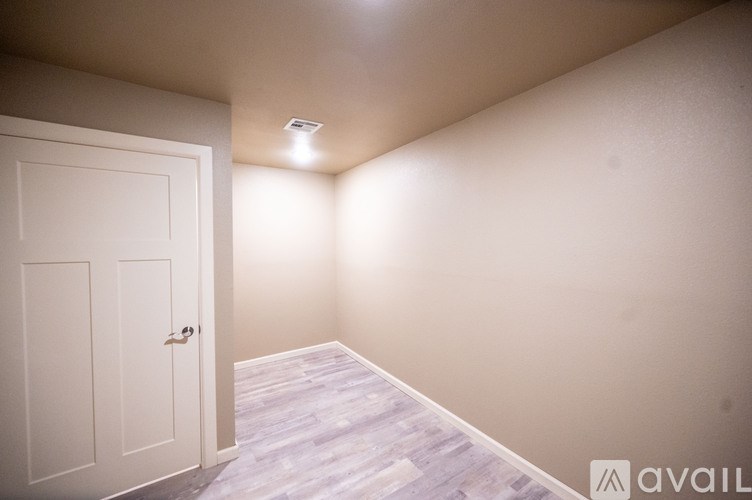 A room with a white door and wooden flooring.