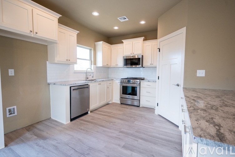 A kitchen with white cabinets and a wooden floor.