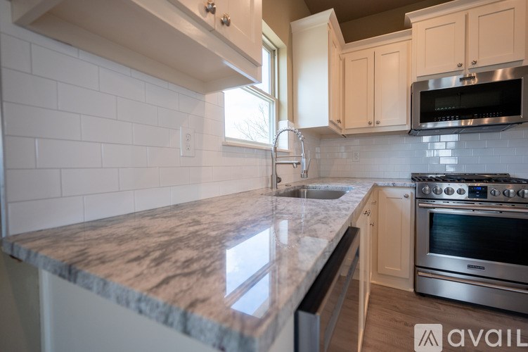 A kitchen with a marble countertop and stainless steel appliances.