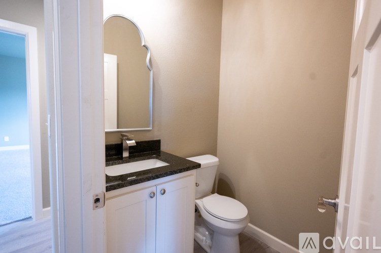 A bathroom with a toilet, sink, and mirror.