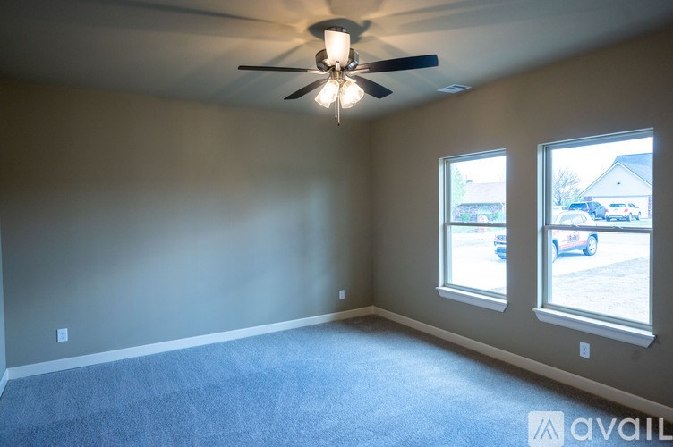 A room with a ceiling fan and two windows.