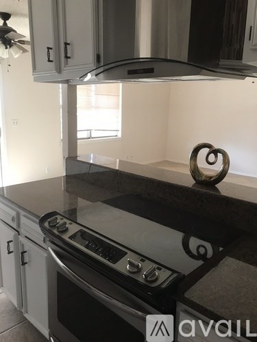 A kitchen with a black countertop and a stove top oven.