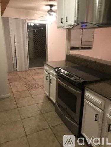 A kitchen with a stove top oven and white cabinets.