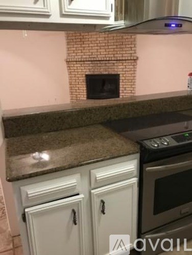 A kitchen with a brick fireplace and granite countertops.