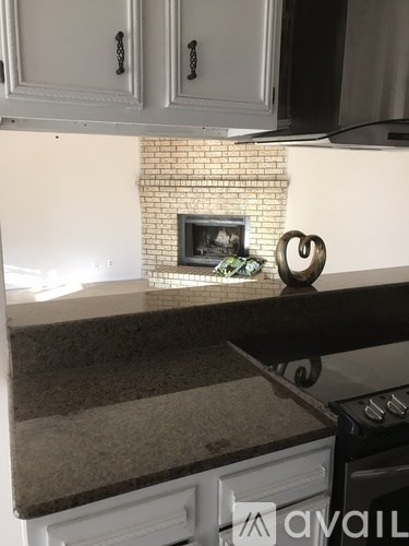A kitchen with a white brick fireplace and a countertop with a silver sculpture on it.