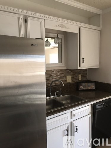 A kitchen with a stainless steel refrigerator and white cabinets.