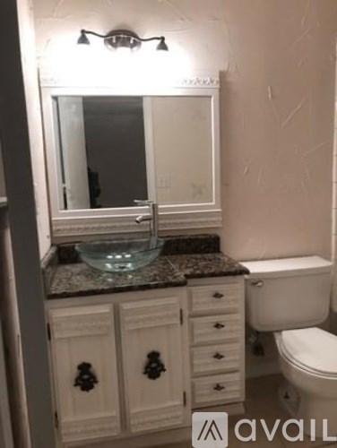 A bathroom with a toilet, sink, and cabinets.