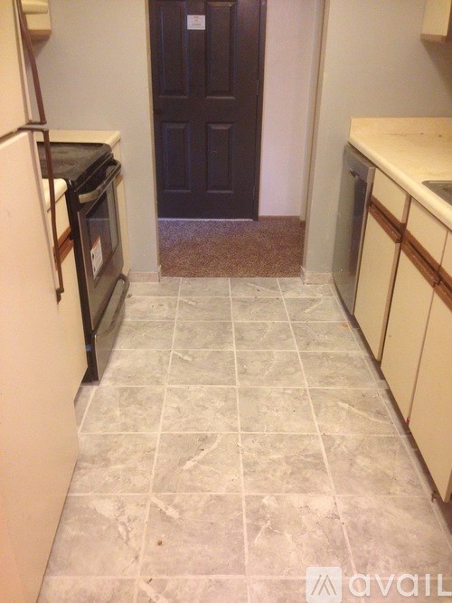 A kitchen with a black door in the middle.