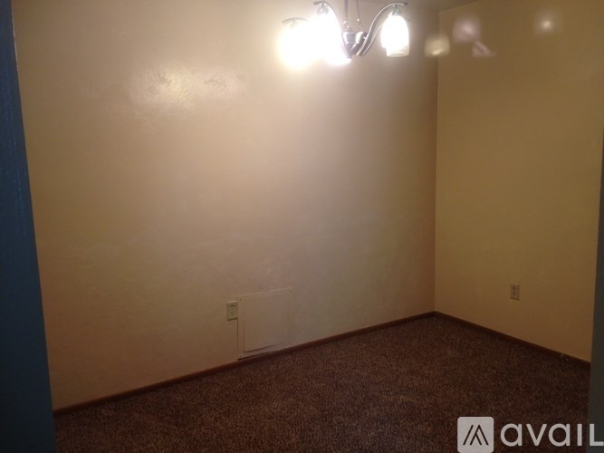 A room with a carpeted floor and a wall-mounted light fixture.