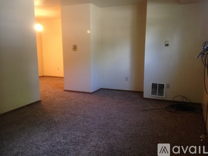 A carpeted room with a window and a wall-mounted air conditioning unit.