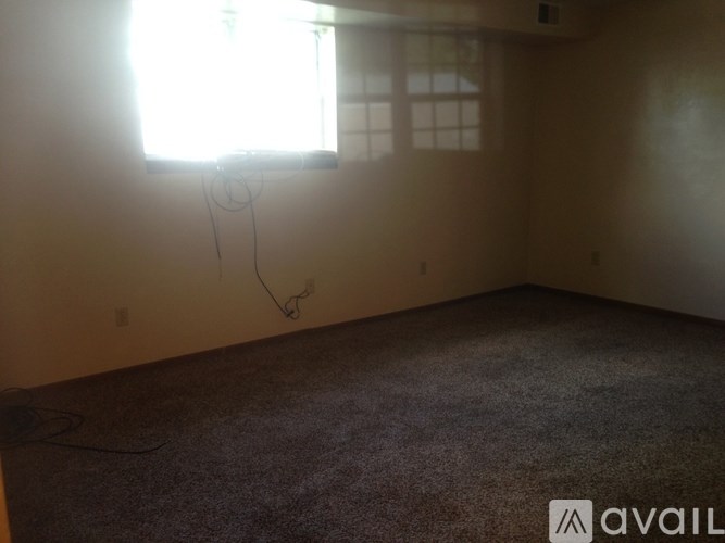 A room with a window and a carpeted floor.