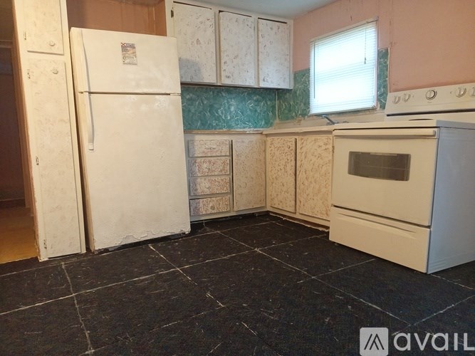 A kitchen with a white refrigerator, oven, and cabinets with a black tile floor.
