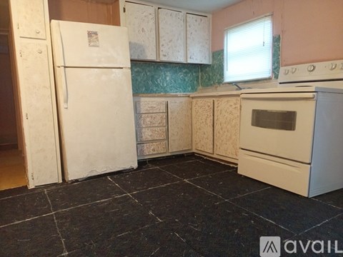 A kitchen with a white refrigerator, oven, and cabinets with a black tile floor.