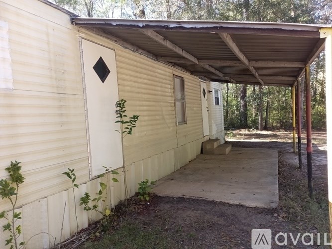A small, beige, single-story house with a covered porch.
