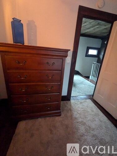 A brown wooden chest of drawers with a blue vase on top.