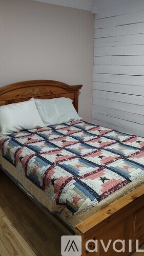 A bed with a wooden headboard and a quilt with a red, white and blue design.