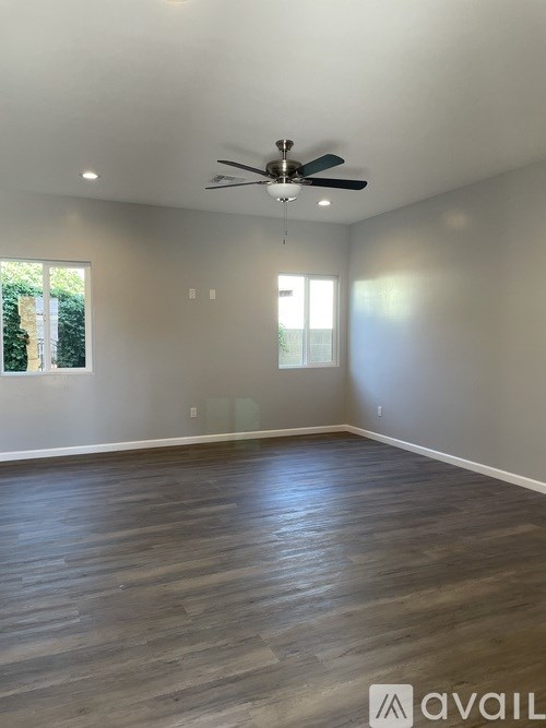 A room with a ceiling fan and wooden flooring.