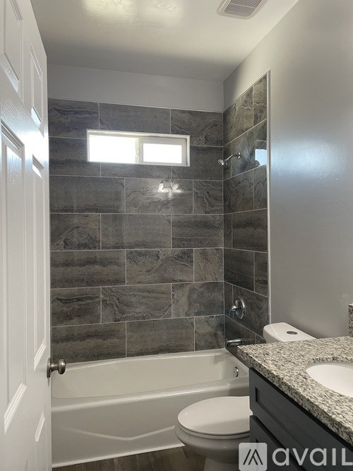 A bathroom with a tiled wall and a white toilet.