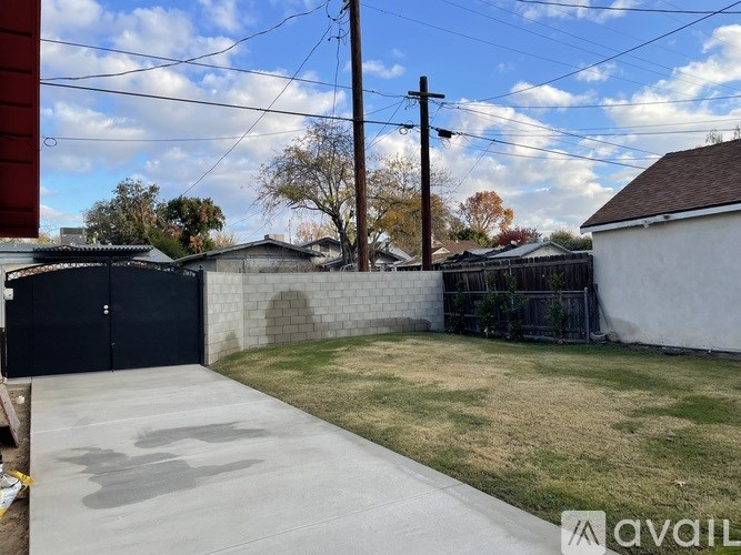 A backyard with a concrete pathway, a fence, and a utility pole.