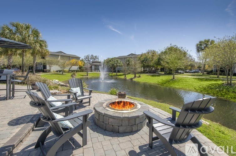 A patio with chairs and a fire pit in the middle of a grassy area.