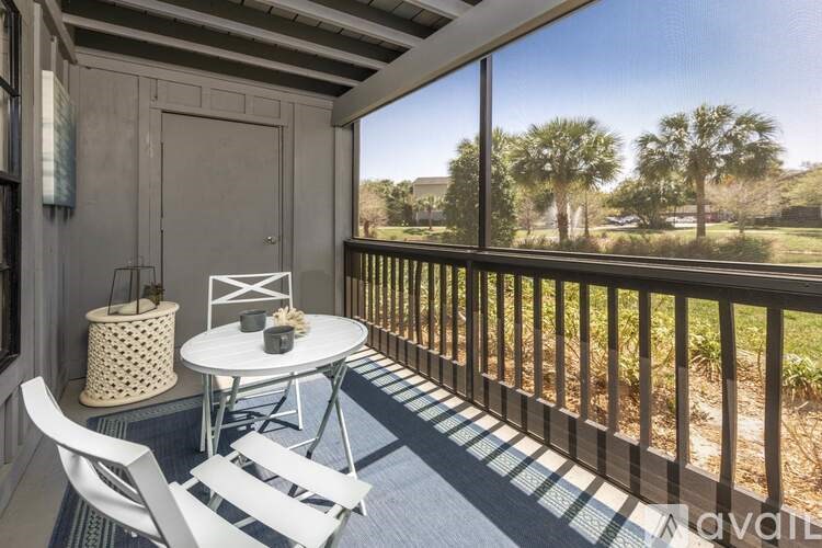 A balcony with a table and chairs overlooking a grassy area.