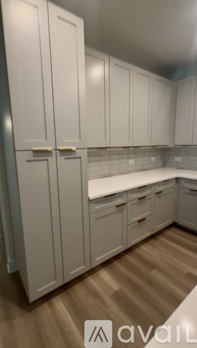A kitchen with white cabinets and a wooden floor.
