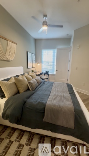A bedroom with a bed in the center and a window with blinds on the right side.