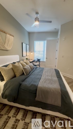 A bedroom with a bed in the center and a window with blinds on the right side.