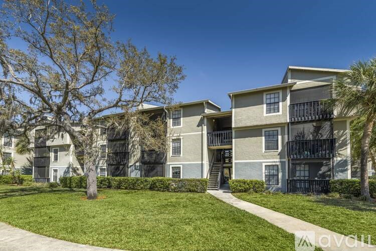 Apartments with balconies and a tree in front.