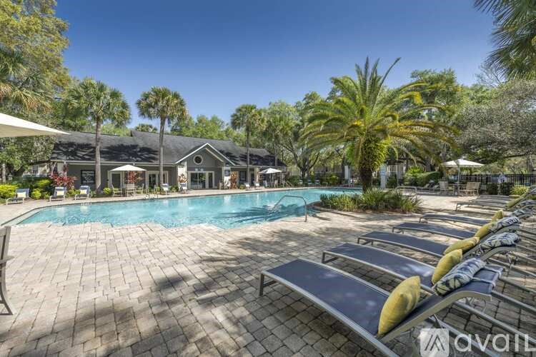 A pool area with sun loungers and a building in the background.