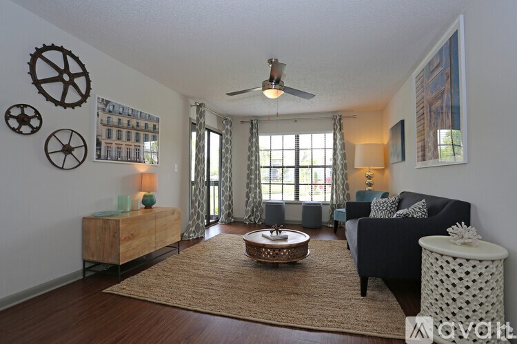 A living room with a black couch, a wooden coffee table, and a ceiling fan.
