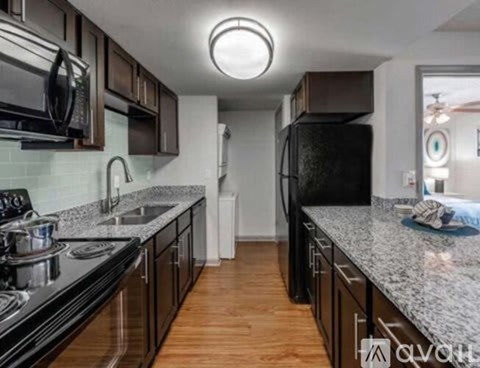 A kitchen with black appliances and wooden floors.