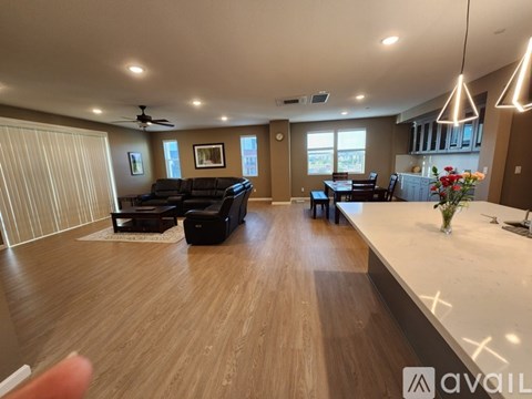 A spacious living room with a black sofa and a wooden floor.