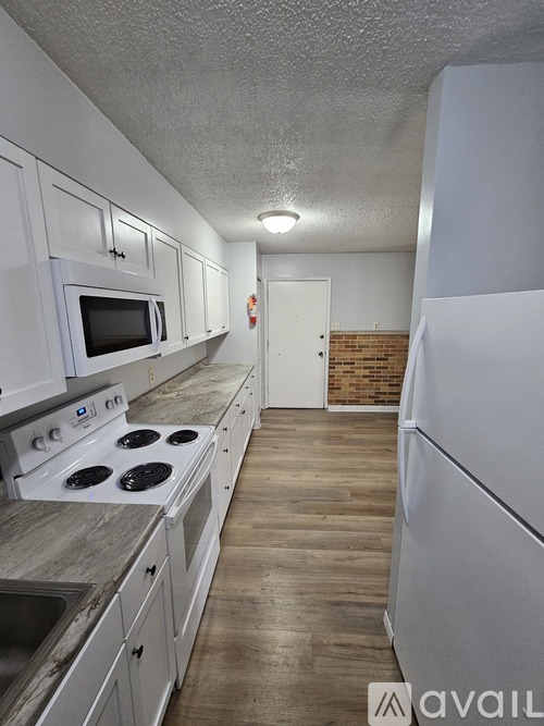 A spacious empty room with a ceiling fan and a door leading to another room.