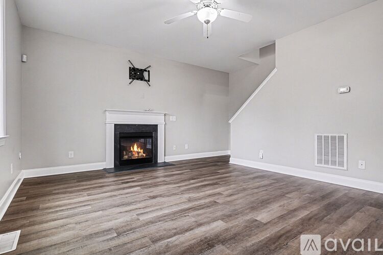 A spacious room with beige carpeting and a window with curtains.