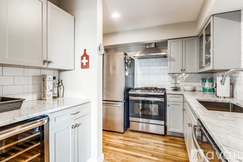 A kitchen with white cabinets and a red cross on the wall.