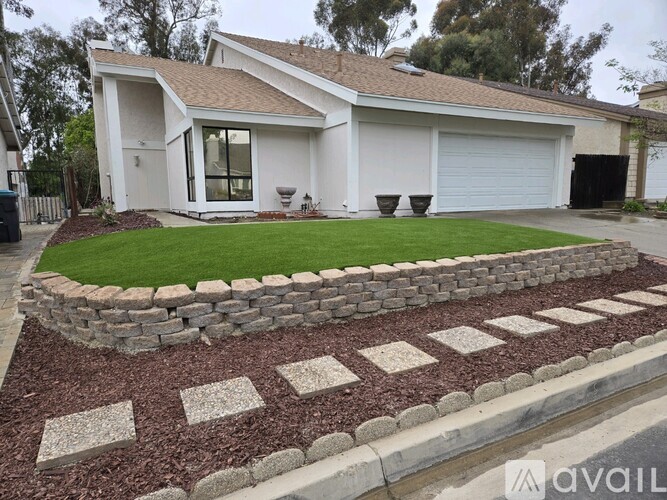 A house with a white exterior and a stone wall in front.
