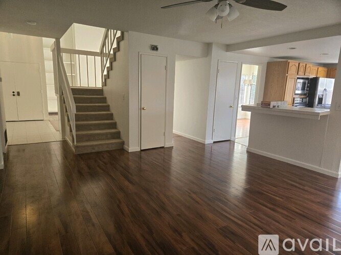 A spacious room with wooden floors and a staircase leading to another level.