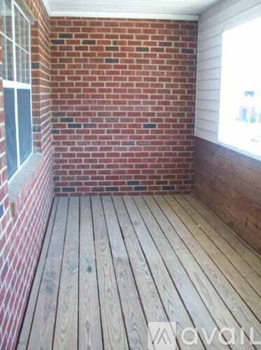 A room with wooden flooring and a brick wall.