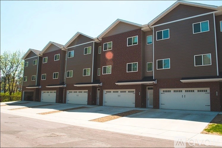 Apartment building with brown and grey exterior and white garage doors.