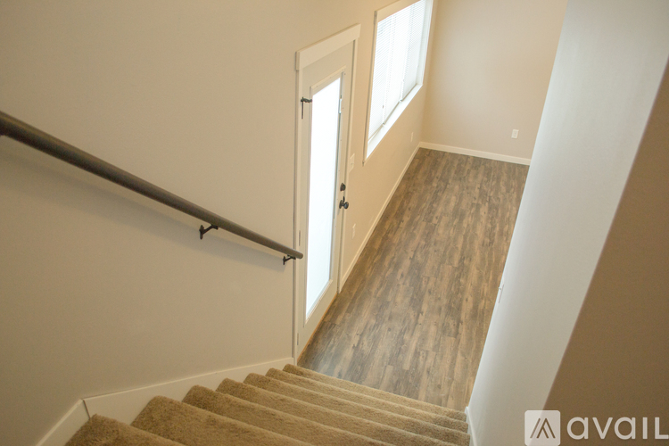 A staircase with a carpeted runner and wooden steps leading to a door.