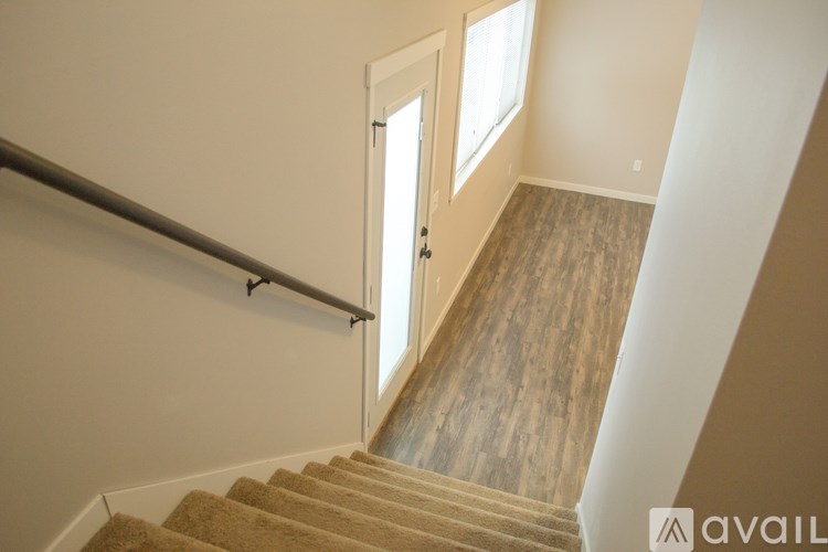 A staircase with a carpeted runner and wooden steps leading to a door.