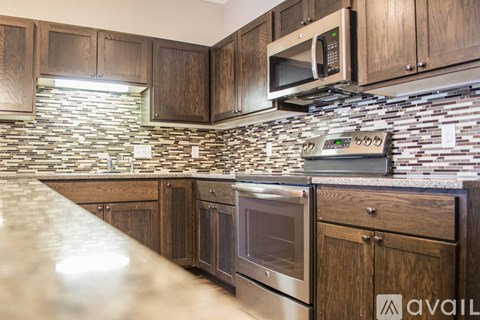 A kitchen with wooden cabinets and a stone backsplash.